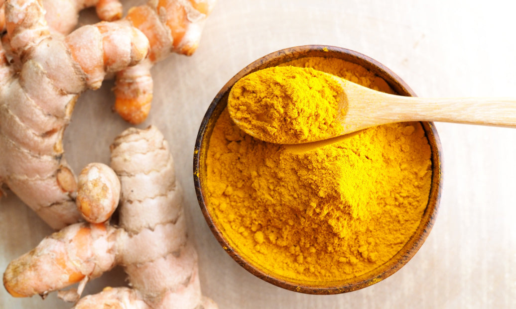 turmeric root next to a bowl with ground turmeric