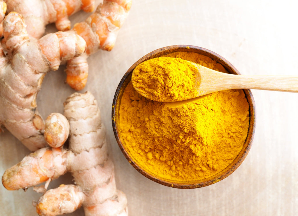 turmeric root next to a bowl with ground turmeric