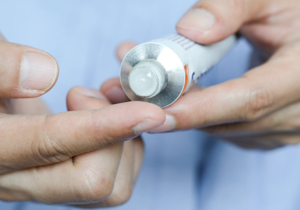 Squeezing steroid cream out of a tube onto a finger before applying