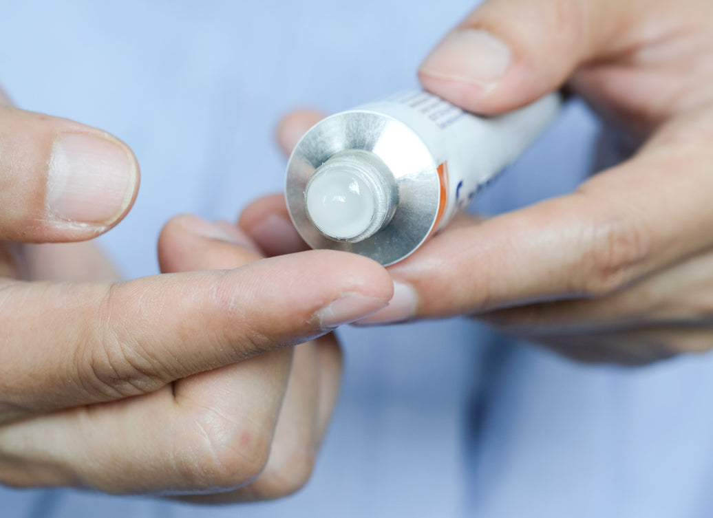 Squeezing steroid cream out of a tube onto a finger before applying