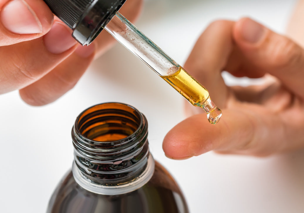 dropping some oil onto a finger from a bottle using a pipette